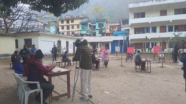 जिल्ला सरमुकामस्थित नमूना माध्यमिक विद्यालय, खलंगा मतदान केन्द्रमा विहान ठिक ७ बजे नै मतदान गर्न मतपत्र लिदै अपाङ्गता भएका व्यक्ति लगायत मतदाताहरू । फोटोः नरेन्द्रसिंह कार्की/दार्चुला